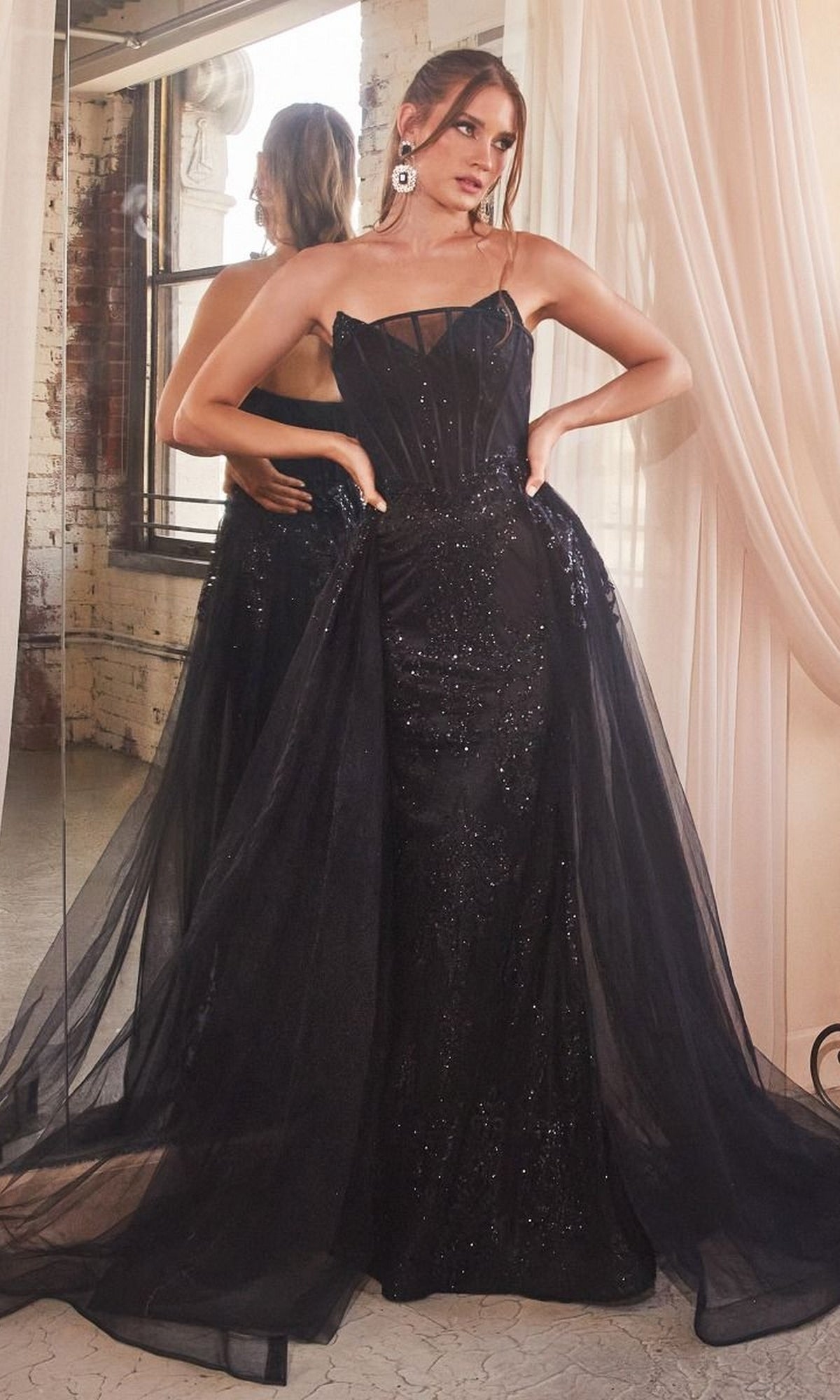 Woman in a Glitter-Print Strapless Long Prom Dress J858 poses in front of a mirror with hands on hips, standing in a room with draped curtains and a large window.